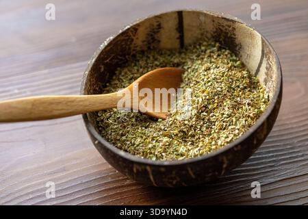 A close-up view of aromatic dried thyme served in a rustic coconut shell bowl. The natural texture and earthy tones emphasize the organic and traditio Stock Photo
