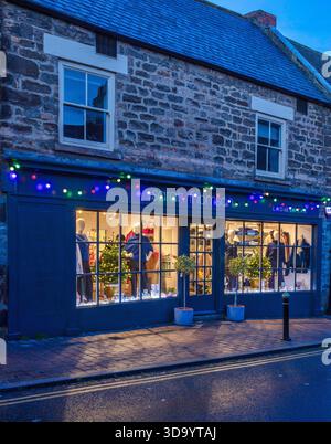 A view at dusk at Christmas of decorated & illuminated shop fronts in Corbridge village, Northumberland Stock Photo