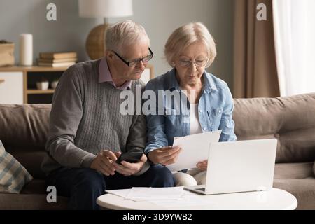 Busy older couple engaged in finance paperwork at home office Stock Photo