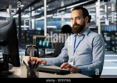 Developer in data center office doing software updates, verifying neural network parameters. Server farm employee using PC to inspect configurations, ensuring optimal application performance Stock Photo
