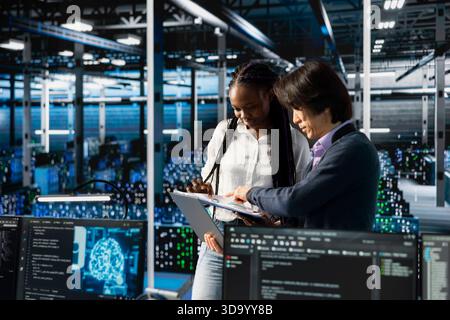 Team leader in data center teaching intern to optimize hardware for AI tasks. Server hub IT manager guiding trainee learning to automate systems using deep learning during internship Stock Photo