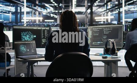 Irritated data center engineer punching desk, irked by glitches while using algorithms to analyze datasets. Mad server hub developer raging, annoyed by malfunctioning AI neural networks, camera A Stock Photo