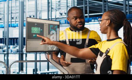 System administrators in smart factory collecting and analyzing data. Coworkers doing brainstorming, using tracking software in industrial plant equipped with advanced sensors, camera A close up Stock Photo