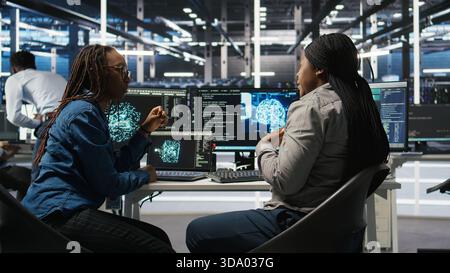 Data center engineering team deploying AI solutions optimizing gear. Server hub teamworking colleagues working together, using artificial intelligence to minimize systems downtime, camera A Stock Photo