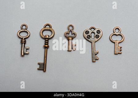 A row of vintage bronze keys lies neatly arranged on a bright surface. Ideal for symbolism, security themes, mystery visuals, creativity and conceptua Stock Photo
