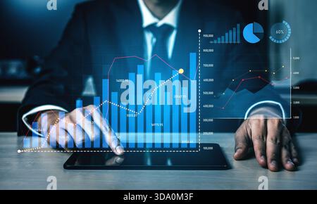 Businessman using a digital tablet to analyze financial data with modern graphs and charts in a professional office, symbolizing growth and strategic Stock Photo