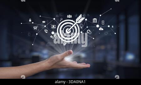 A hand emerges from a modern office background, presenting a digital target icon along with various technology symbols, illustrating the concept of Stock Photo