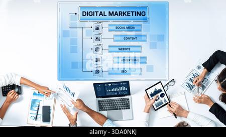 A team collaborates on a digital marketing strategy, utilizing various devices and analyzing charts. The focus is on effective teamwork and data Stock Photo