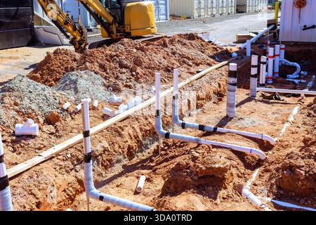 Workers are laying down pipes in trench at construction site for drainage system Stock Photo
