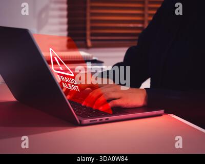 Business person or user receiving a red fraud alert warning on virtual screen. Cybersecurity risks, financial fraud, online scams, scammer attack, dat Stock Photo