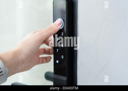 Close up finger pushing illuminated button on smart door lock keypad symbolizing secure access technology safety protection convenience modern living Stock Photo