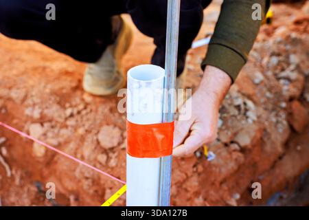Worker measures position of pipe on construction site with tape tools Stock Photo