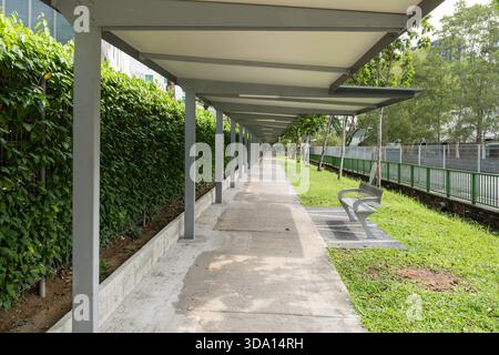 A modern walkway featuring a shaded seating area along Orchard Road in Singapore, surrounded by lush greenery and a clean, inviting atmosphere for ped Stock Photo