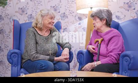 Elderly women talking in nursing home lounge area Stock Photo