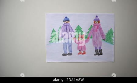 Close up photo of child's drawing. A family, parents and kid in bright winter clothes standing with pine trees. Winter walking. Light background. On t Stock Photo
