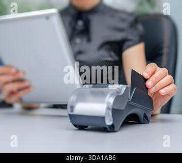A person is using a portable point-of-sale terminal to process a transaction with a credit card Stock Photo