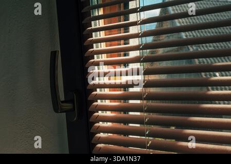 Sunlight streaming through window blinds, casting striped shadow pattern indoors. Selective focus. Stock Photo
