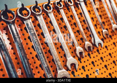 Rome, italy 20 november 2025: metal wrenches neatly organized on an orange pegboard, ready for repair and maintenance tasks in a professional garage o Stock Photo
