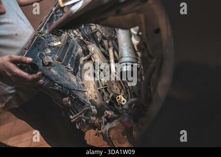 Rome, italy 20 november 2025: mechanic's dirty hands inspecting and replacing worn auto parts in an engine bay during maintenance and repair work in a Stock Photo