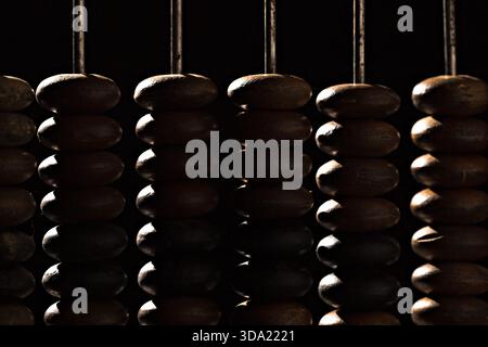 Wooden beads lined up in rows on a dark background during evening light Stock Photo