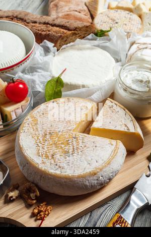 Cheese platter with assorted cheeses, bread, and garnishes on wooden background Stock Photo