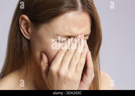 Studio shot of a young woman suffering from symptoms of sinus Infection (Sinusitis) Stock Photo
