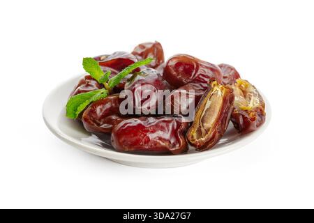 Delicious fresh dates served on a white plate with mint leaves for decoration Stock Photo