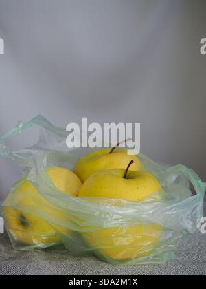 Yellow Apples In Single-Use Plastic Bag On Table - Non Eco Friendly Fruit Packaging Concept Stock Photo