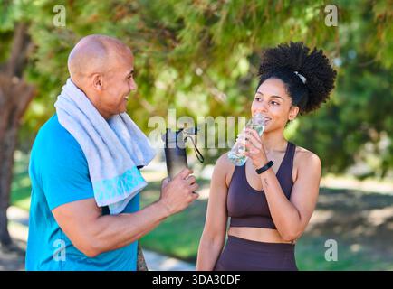 Friends Hydrating After Outdoor Workout: Man With Towel And Woman Drinking Water In Park Together Stock Photo