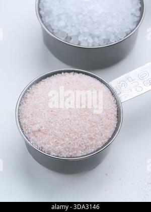Pink Himalayan Salt and Sea Salt in Metal Measuring Cups Stock Photo