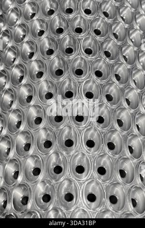 Embossed surface of perforated stainless steel cylinder, close-up shot, abstract background Stock Photo
