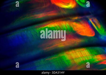 Abstract image of blurred, flowing light streaks in red, green, blue, and orange tones on a dark background, forming layered, wave-like patterns with Stock Photo