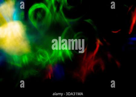Abstract image of swirling green, red, blue, and yellow light forms on a dark background, with soft blurred shapes, circular motions, glowing streaks, Stock Photo