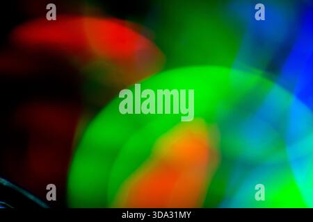 Abstract image of soft blurred light shapes in green, red, blue and orange tones on a dark background, with overlapping circular forms, smooth gradien Stock Photo