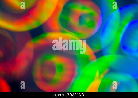 Abstract image of soft blurred circular light shapes in red, green, blue and yellow tones, overlapping on a dark background with smooth gradients, glo Stock Photo