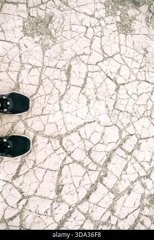 Overhead view of a person's trainers on cracked earth in Death Valley National Park, California, USA Stock Photo
