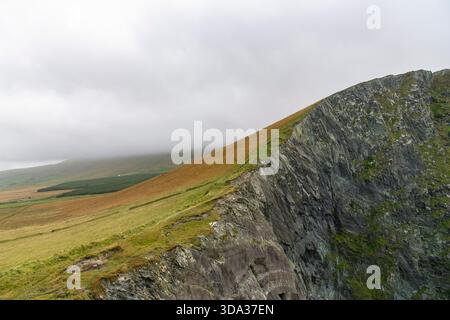 Dark clouds draped over the rolling hills of agricultural landscape next to the Kerry Cliffs in Ireland Stock Photo