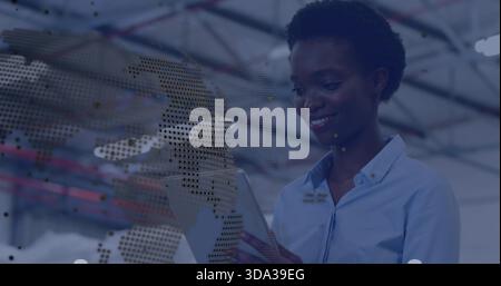 Using engineer wearing blue shirt checking tablet inside warehouse, dotted map overlay, copy space Stock Photo