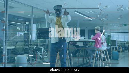 Pointing man wearing VR headset, light cardigan and yellow shirt, interacting with HUD in office Stock Photo