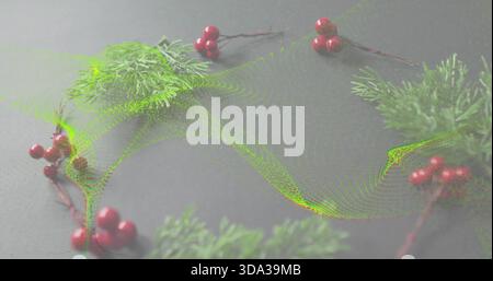 Displaying wreath of evergreen sprigs and red berries on gray tabletop, showing green particle wave Stock Photo