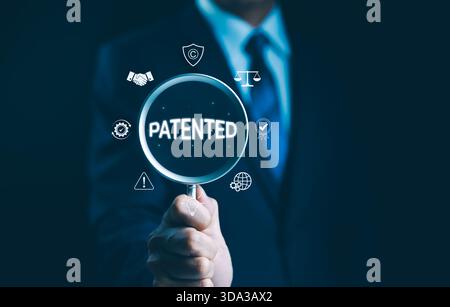 Patented Concept. Patented patent copyright law business technology, Businessman holding magnifying glass focused on word "Patented," with icons of co Stock Photo
