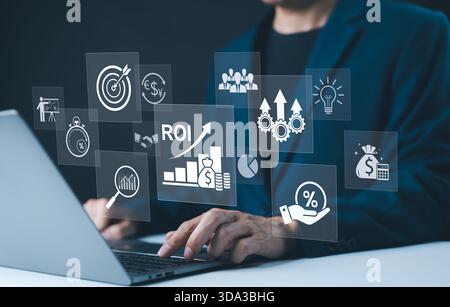 Analyzing ROI and Business Strategy Concepts. Businessman working on a laptop with various digital icons representing ROI, financial strategies, retur Stock Photo