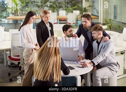 Colleagues Collaborating On Laptop And Documents In Office Meeting Stock Photo