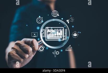Analyzing online advertising campaigns and performance. A magnifying glass focusing on "Ads" with icons representing various elements of online advert Stock Photo