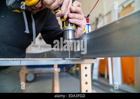 Man using power tool drilling metal bar in a workshop Stock Photo