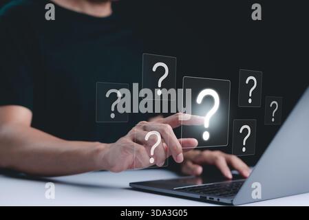 Question Mark and Problem Solving Concept. A person using a laptop with floating question marks, symbolizing brainstorming, problem-solving, and findi Stock Photo