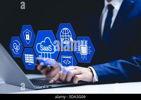 SaaS Concept, Software as a Service, Businessman types on laptop with icons representing aspects of Software as a Service (SaaS), modern technology pl Stock Photo