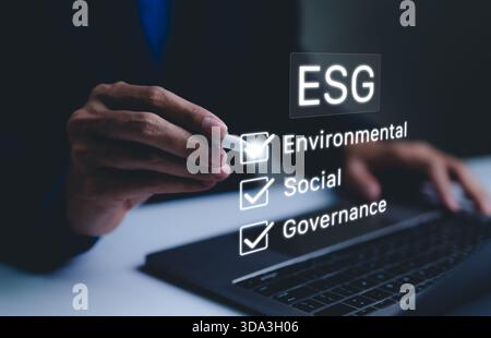 ESG Concept for Environmental, Social, and Governance. Businessman checking off ESG factors Environmental, Social, Governance on virtual screen, Stock Photo