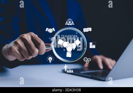 Teamwork and collaboration concept. Businessman holds magnifying glass focused on "Teamwork" icon symbols collaboration, communication, and idea Stock Photo