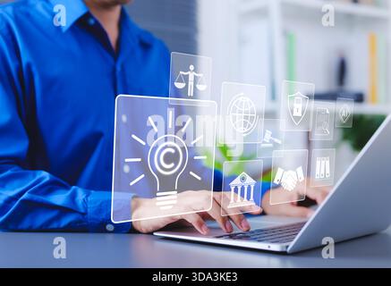 Copyright and intellectual property protection concept. Man using laptop with digital icons representing copyright, intellectual property, legal Stock Photo